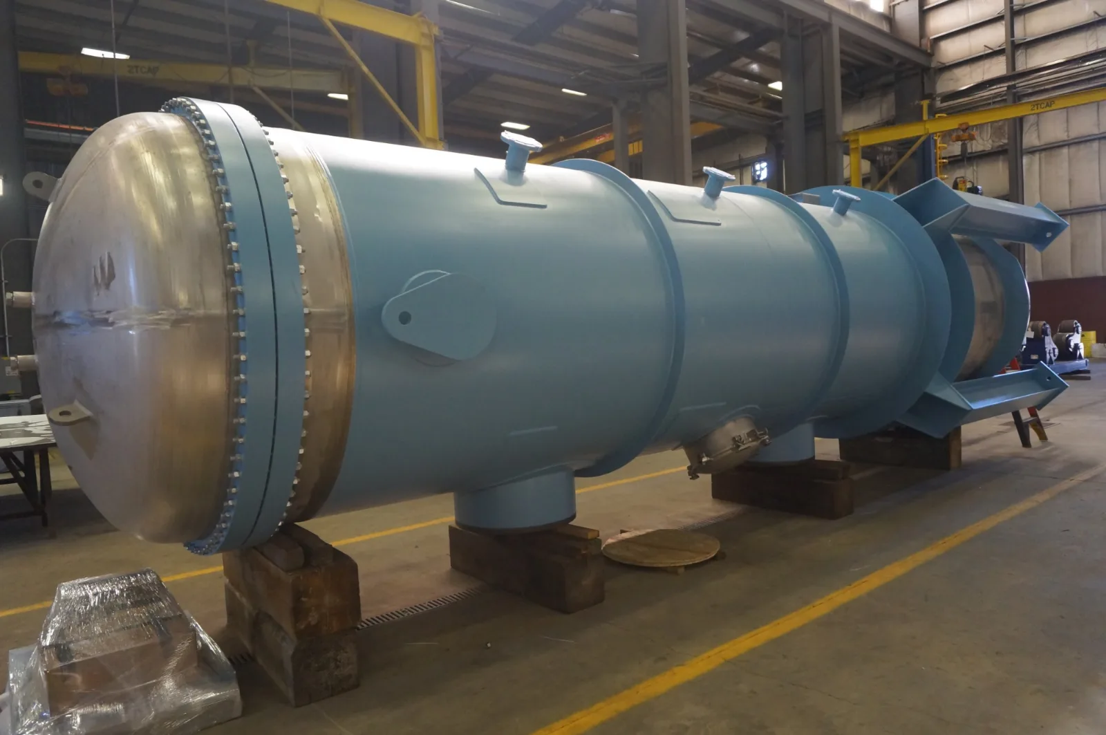 Blue-coated fabricated pressure vessel with bolted head closure on saddle supports in the Harris Thermal shop