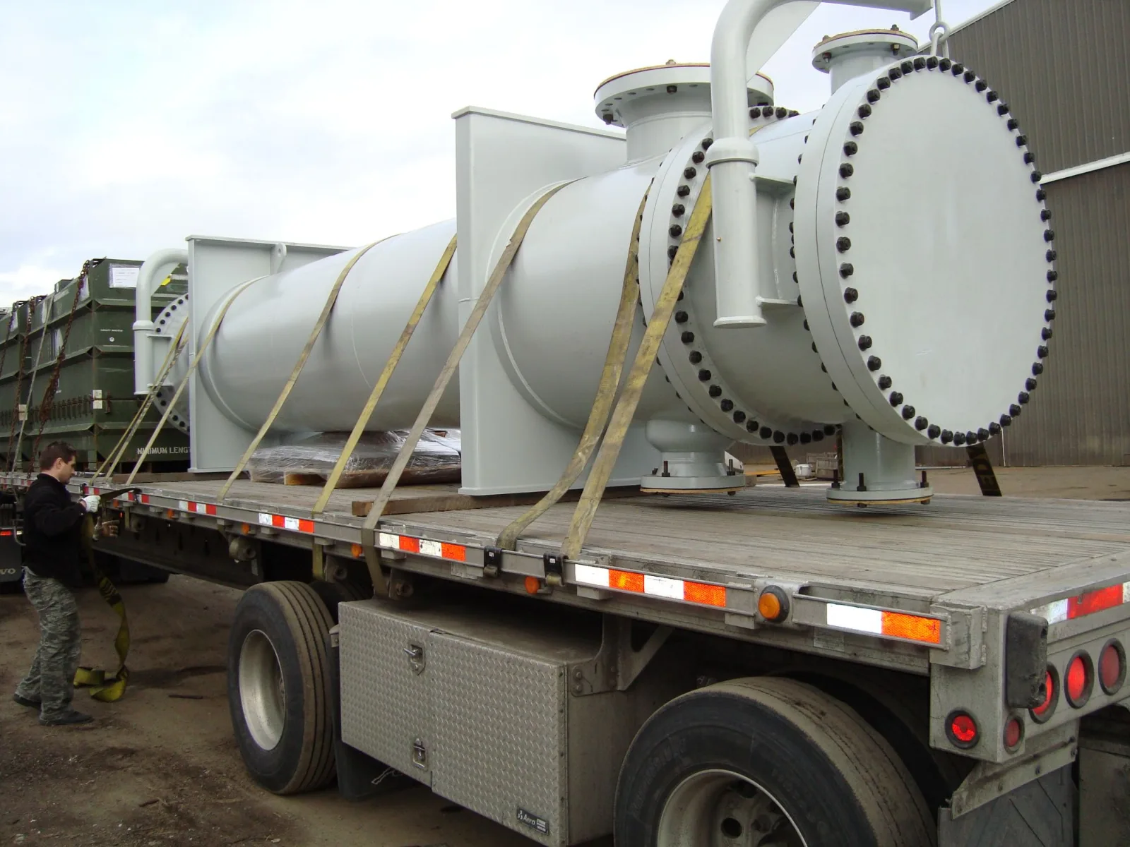 Fabricated shell-and-tube heat exchanger with bolted channel head, loaded on a flatbed trailer for shipment