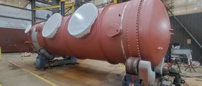 Primer-coated horizontal pressure vessel with protected nozzles on turning rolls
