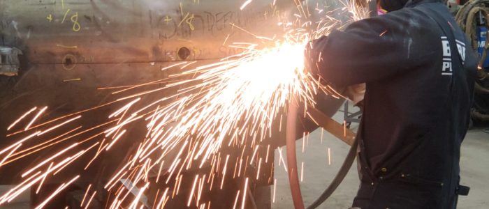 Welder cutting a heavy steel section on the Harris Thermal fabrication floor