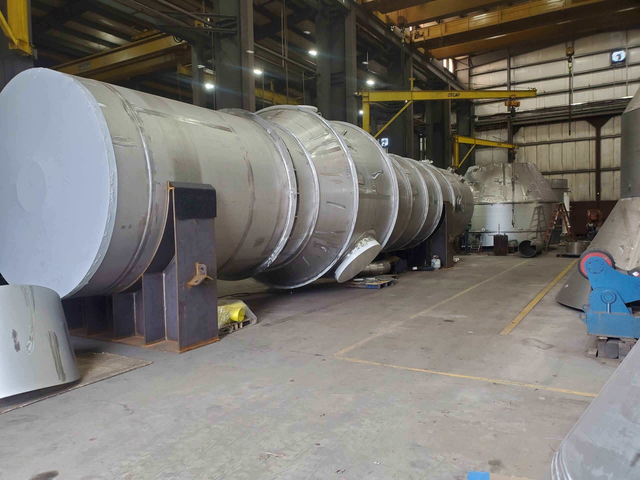 Large stainless steel vessels under fabrication on stands in the Harris Thermal shop