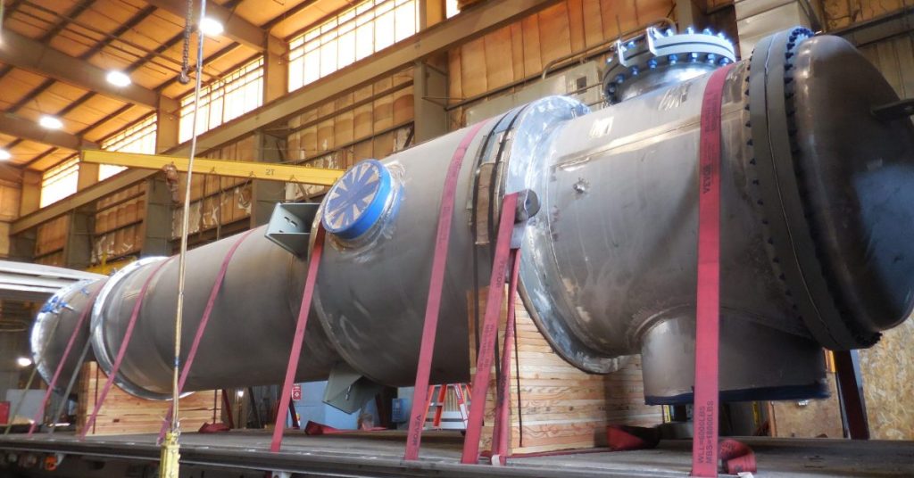 Fabricated process vessel with flanged nozzles strapped to a flatbed trailer in the Harris Thermal shop