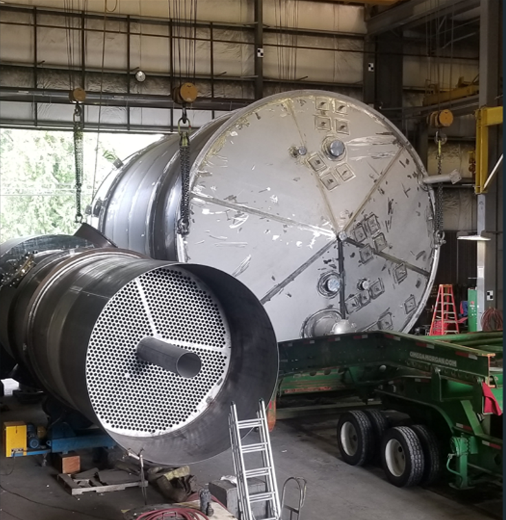 A tall fabricated process column staged on multi-axle transport trailers
